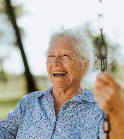 Lachende Seniorin beim Schaukeln