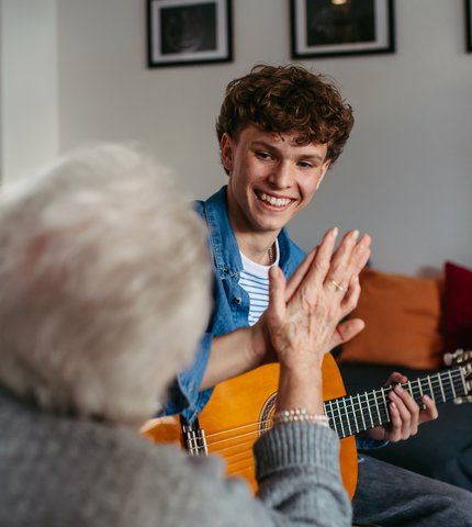 Teenager musiziert mit Seniorin